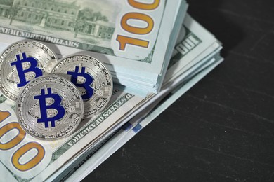 Photo of Cryptocurrency. Bitcoins and dollar banknotes on black table, above view. Space for text