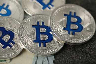 Photo of Cryptocurrency. Bitcoins and dollar banknotes on grey table, closeup