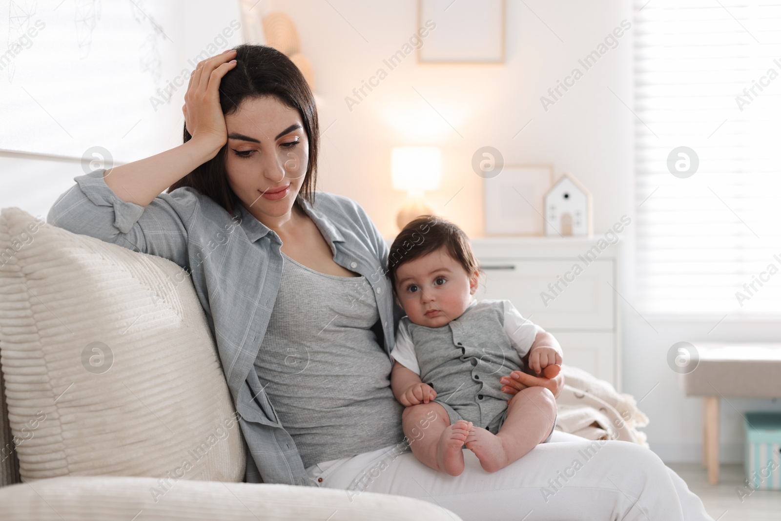 Photo of Woman suffering from postpartum depression with her little baby on sofa at home. Space for text