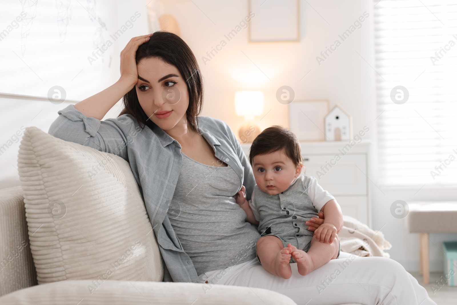 Woman suffering from postpartum depression with her little baby on sofa at home. Space for text Photo of Woman suffering from postpartum depression with her little baby on sofa at home. Space for text