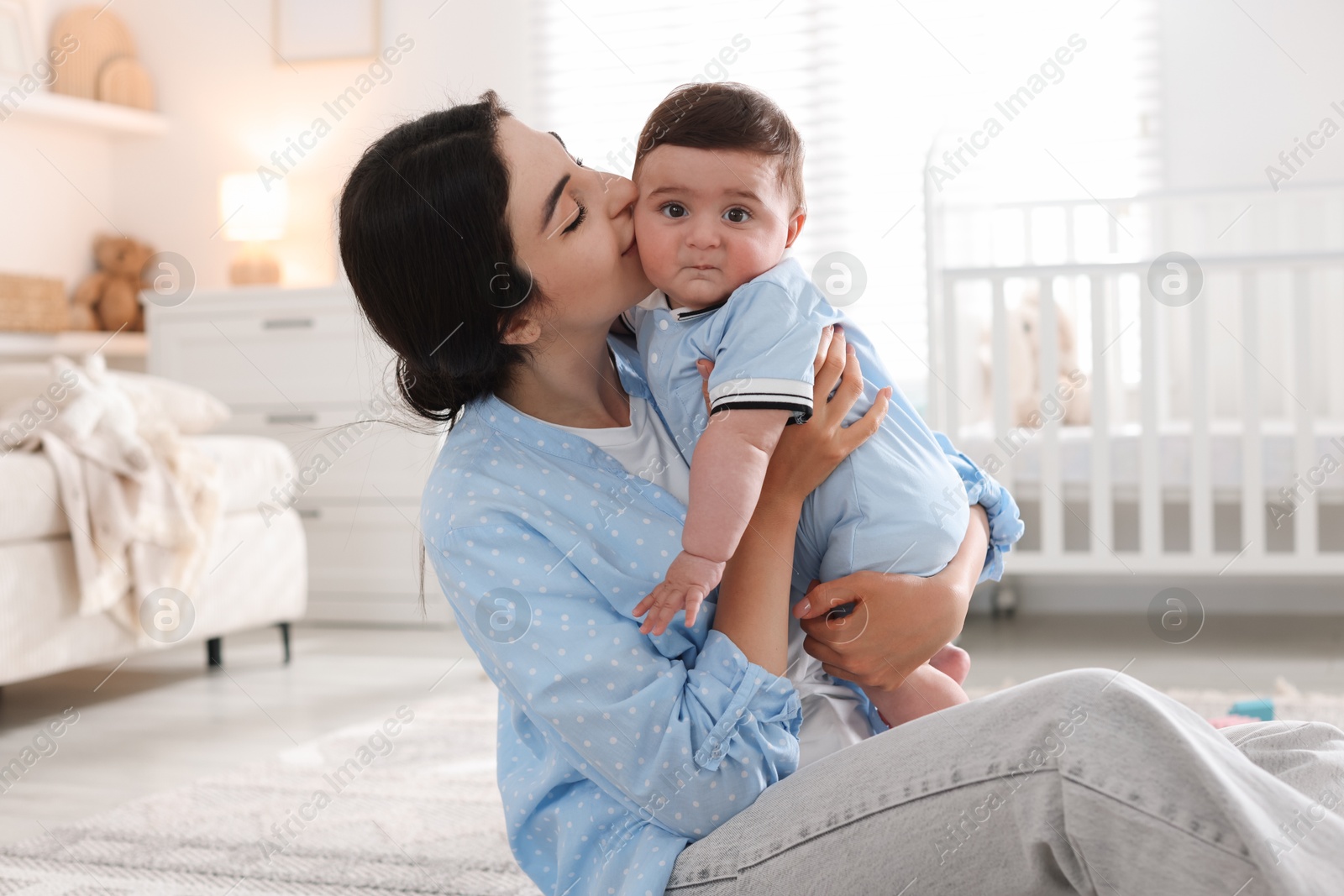 Mother kissing her cute baby at home Photo of Mother kissing her cute baby at home