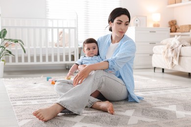 Photo of Woman suffering from postpartum depression with her little baby at home