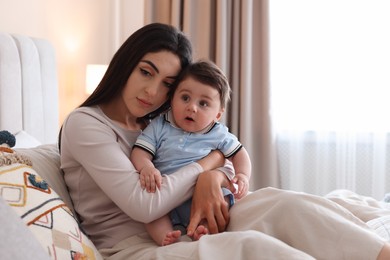 Photo of Woman suffering from postpartum depression with her little baby on bed at home