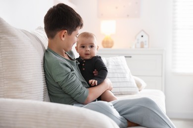 Photo of Cute little brothers sitting on sofa at home