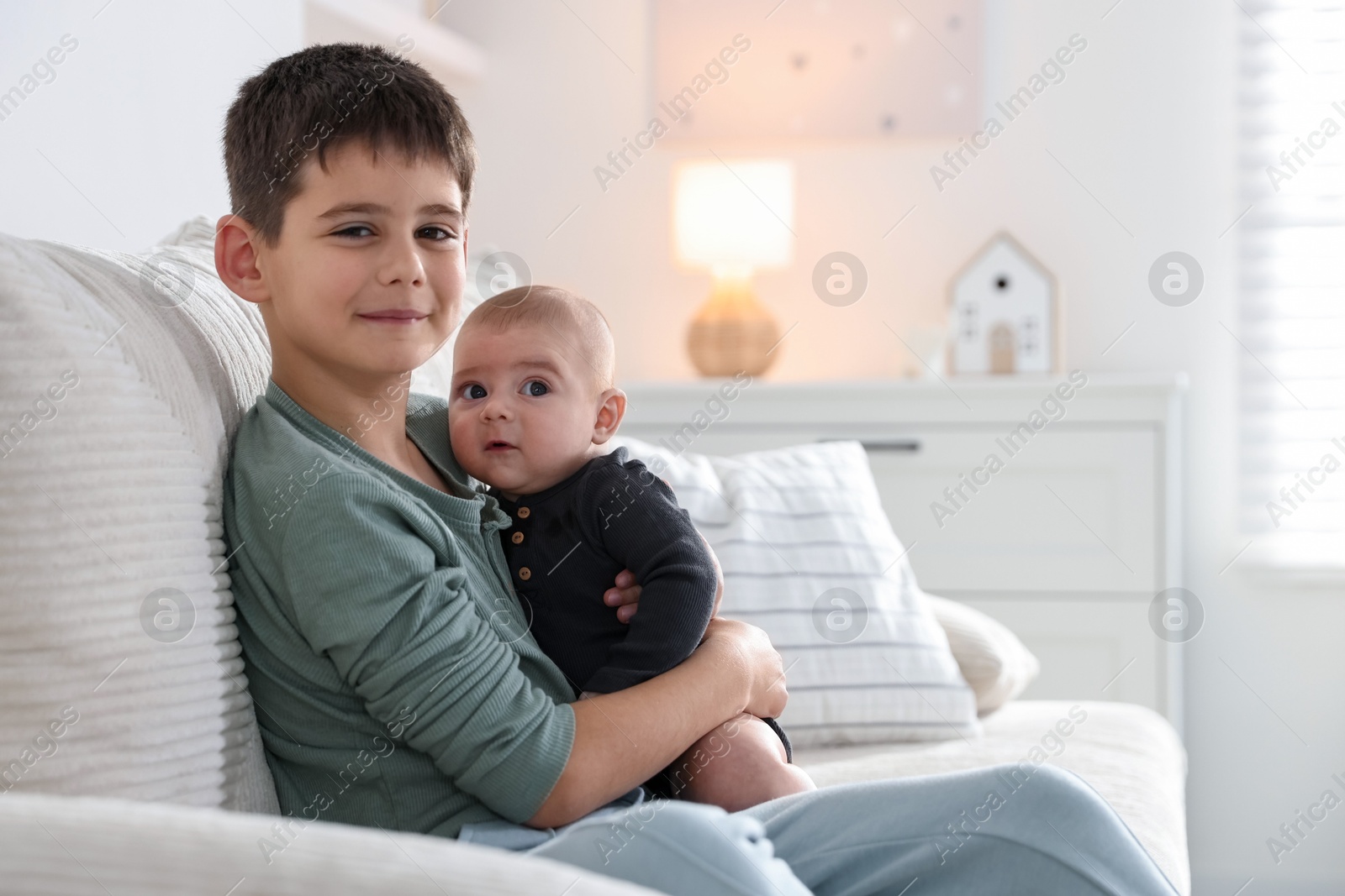 Cute little brothers sitting on sofa at home Photo of Cute little brothers sitting on sofa at home