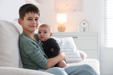 Photo of Cute little brothers sitting on sofa at home