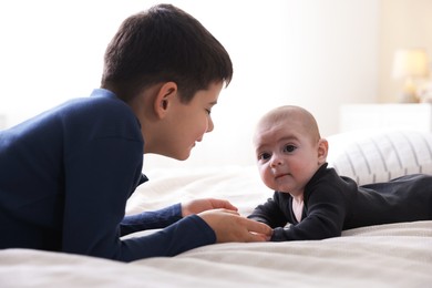 Photo of Cute little brothers holding hands on bed at home