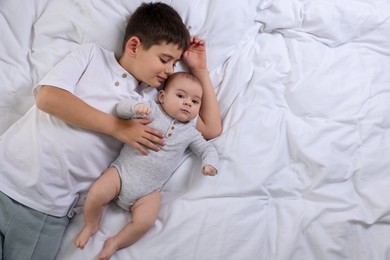 Photo of Cute little brothers on bed, top view. Space for text