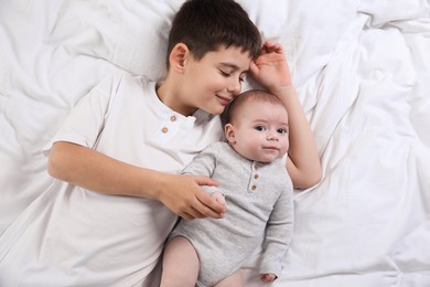 Photo of Cute little brothers on bed, top view