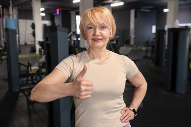 Photo of Senior woman showing thumbs up in gym
