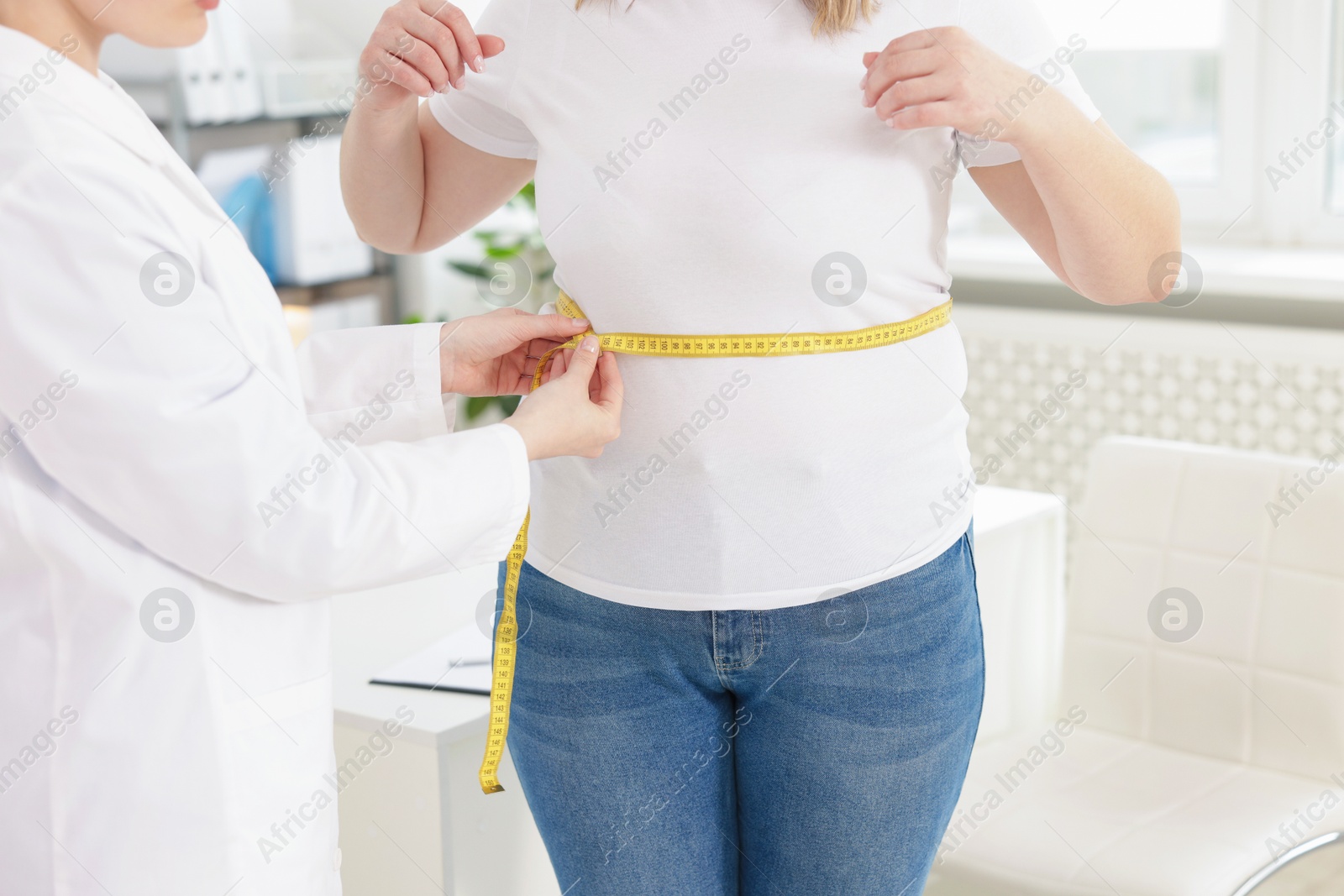 Weight loss. Nutritionist measuring overweight woman's waist with tape in clinic, closeup Photo of Weight loss. Nutritionist measuring overweight woman's waist with tape in clinic, closeup