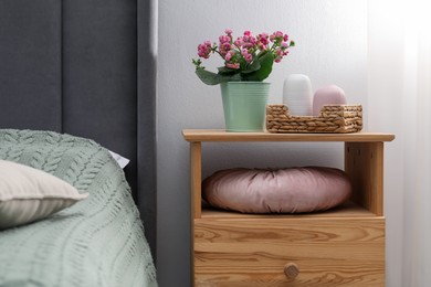 Photo of Bedside table with flowers and decor near bed indoors