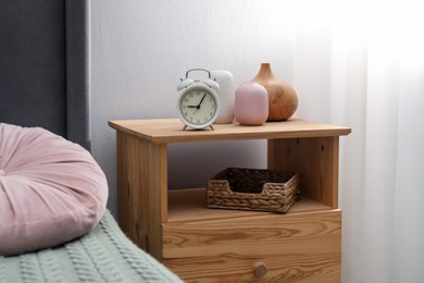 Photo of Bedside table with alarm clock and air humidifier near bed indoors