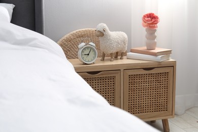 Photo of Bedside table with alarm clock, decor and books near bed indoors