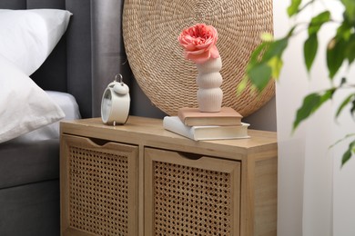 Photo of Bedside table with alarm clock, decor and books near bed indoors