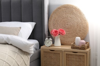 Photo of Bedside table with alarm clock and decor near bed indoors