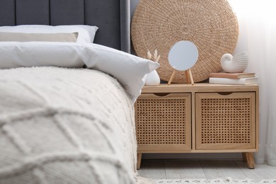 Photo of Bedside table with mirror, decor and books near bed indoors
