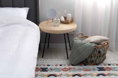 Photo of Side table with mirror, alarm clock and decor near bed indoors
