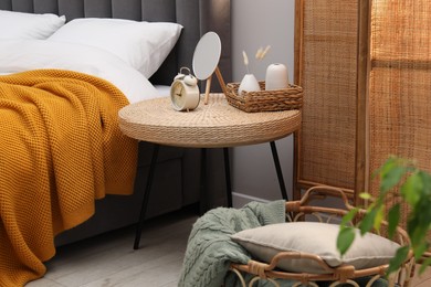 Photo of Side table with mirror, alarm clock and decor near bed indoors
