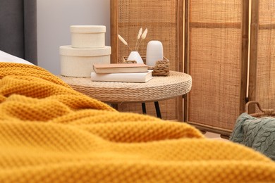 Photo of Side table with books and decor near bed indoors