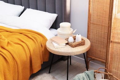 Photo of Side table with books and decor near bed indoors