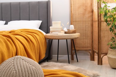 Photo of Side table with books and decor near bed indoors