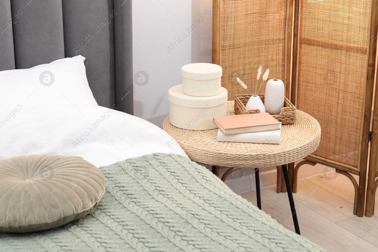 Side table with books and decor near bed indoors Photo of Side table with books and decor near bed indoors