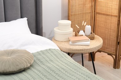 Photo of Side table with books and decor near bed indoors