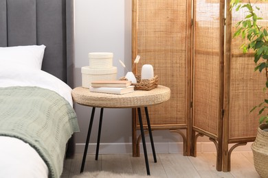 Photo of Side table with books and decor near bed indoors