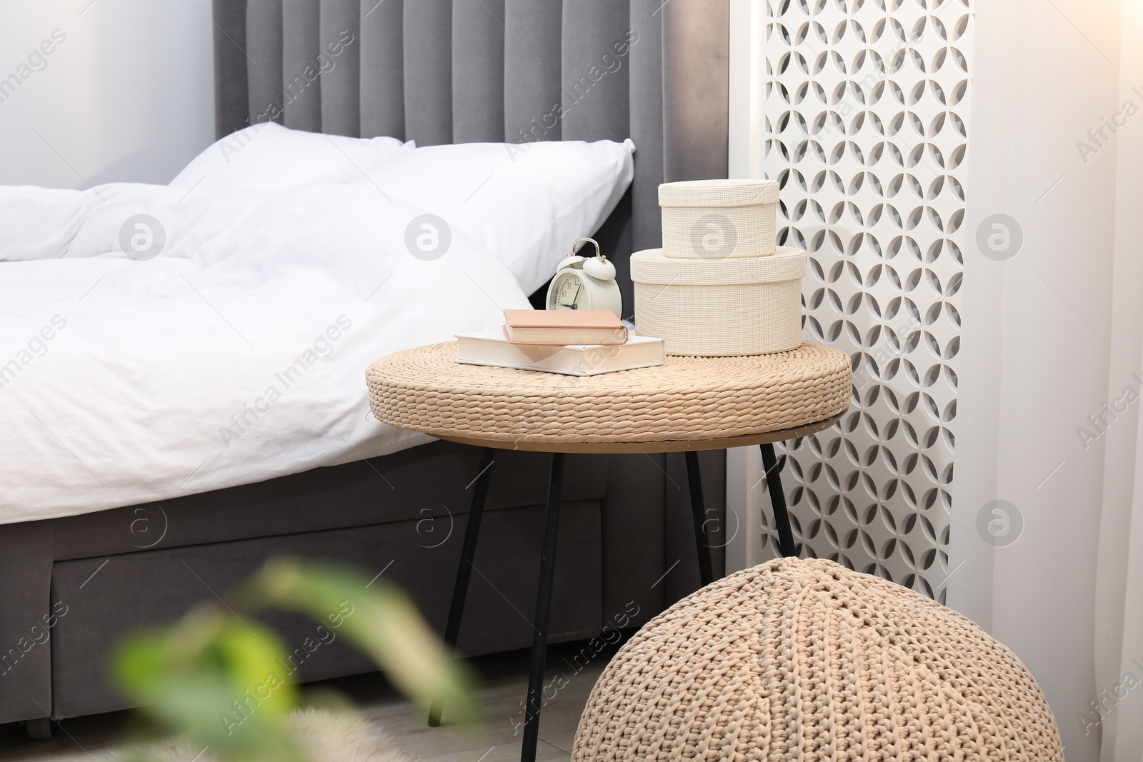 Photo of Side table with alarm clock, books and decor near bed indoors