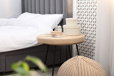 Photo of Side table with alarm clock, books and decor near bed indoors