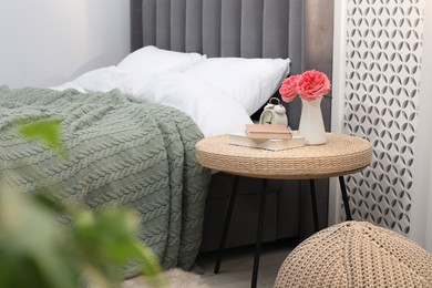 Photo of Side table with alarm clock, books and decor near bed indoors