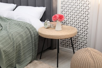 Photo of Side table with alarm clock, books and decor near bed indoors