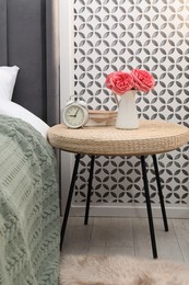 Photo of Side table with alarm clock, books and decor near bed indoors