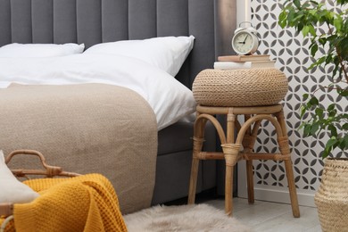 Photo of Side table with alarm clock and books near bed indoors