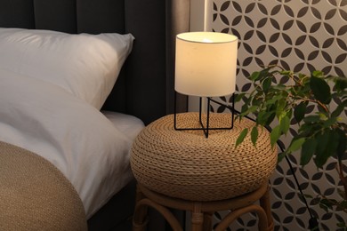 Photo of Side table with lamp near bed indoors