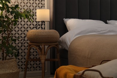 Photo of Side table with lamp near bed indoors