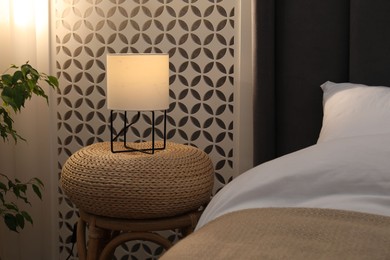 Photo of Side table with lamp near bed indoors