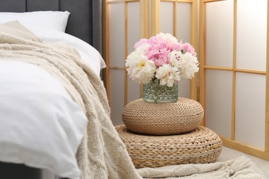 Photo of Side table with flowers near bed indoors