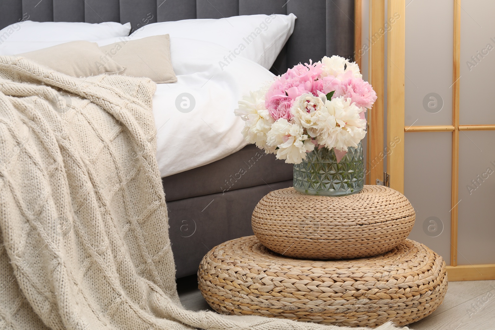 Side table with flowers near bed indoors Photo of Side table with flowers near bed indoors