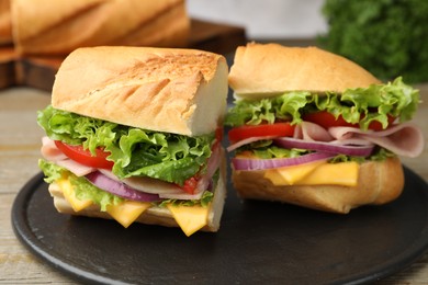 Photo of Pieces of tasty baguette sandwich with ham, cheese and vegetables on wooden table, closeup