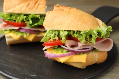 Photo of Pieces of tasty baguette sandwich with ham, cheese and vegetables on wooden table, closeup