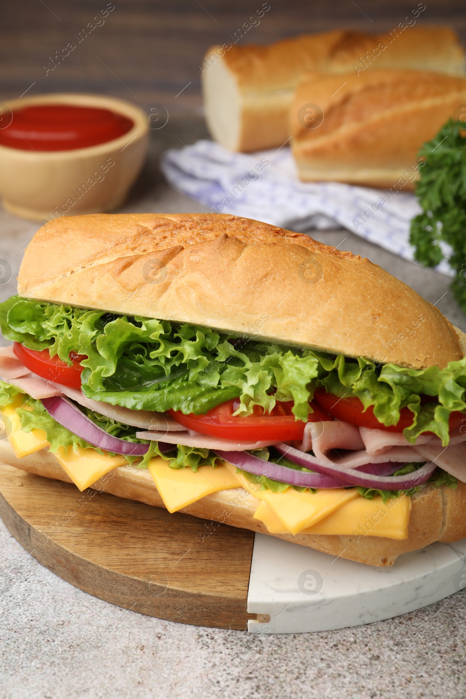 Tasty baguette sandwich with ham, cheese and vegetables on grey textured table, closeup Photo of Tasty baguette sandwich with ham, cheese and vegetables on grey textured table, closeup