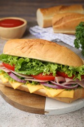 Photo of Tasty baguette sandwich with ham, cheese and vegetables on grey textured table, closeup