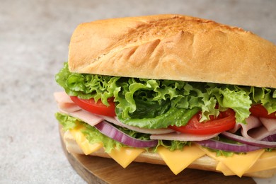 Photo of Tasty baguette sandwich with ham, cheese and vegetables on grey table, closeup