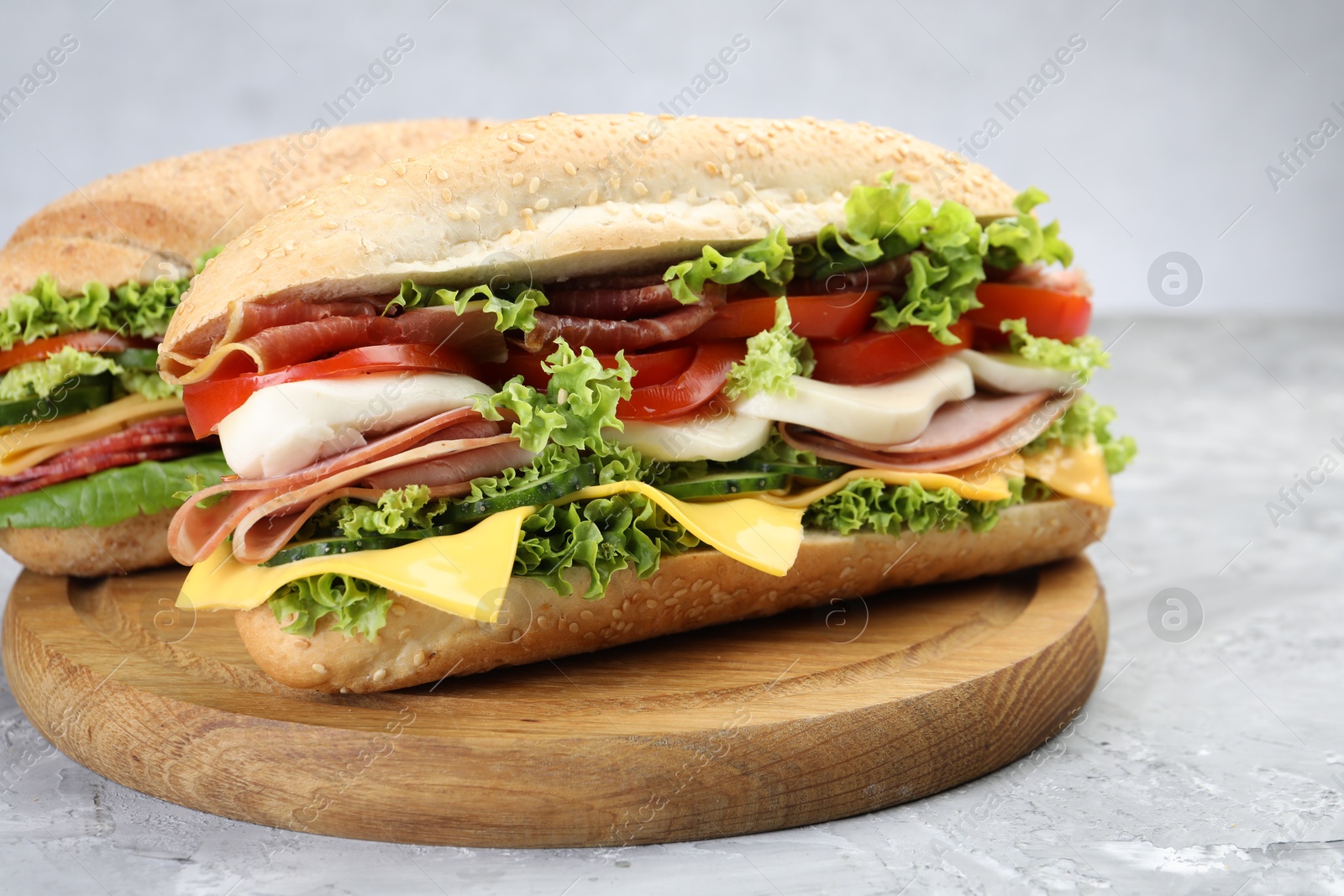 Tasty baguette sandwiches with ham, cheese and vegetables on grey textured table, closeup Photo of Tasty baguette sandwiches with ham, cheese and vegetables on grey textured table, closeup