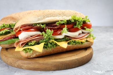 Photo of Tasty baguette sandwiches with ham, cheese and vegetables on grey textured table, closeup