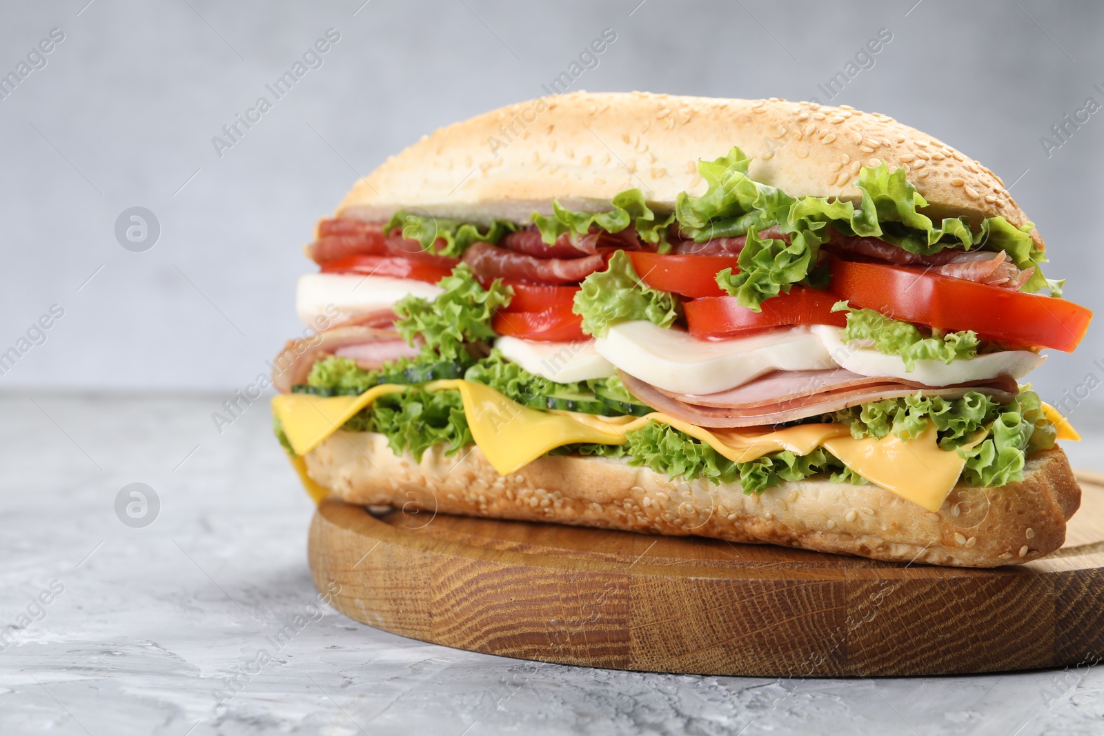 Tasty baguette sandwich with ham, cheese and vegetables on grey textured table, closeup Photo of Tasty baguette sandwich with ham, cheese and vegetables on grey textured table, closeup