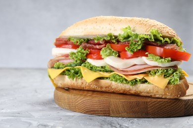 Photo of Tasty baguette sandwich with ham, cheese and vegetables on grey textured table, closeup