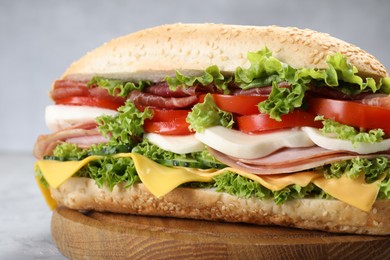 Photo of Tasty baguette sandwich with ham, cheese and vegetables on grey table, closeup